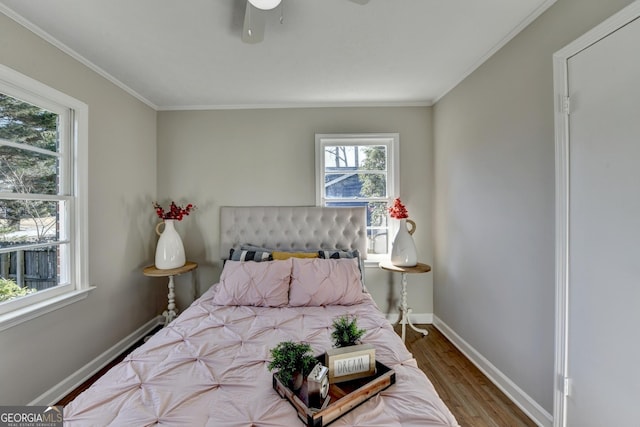 bedroom with hardwood / wood-style floors, multiple windows, ceiling fan, and ornamental molding