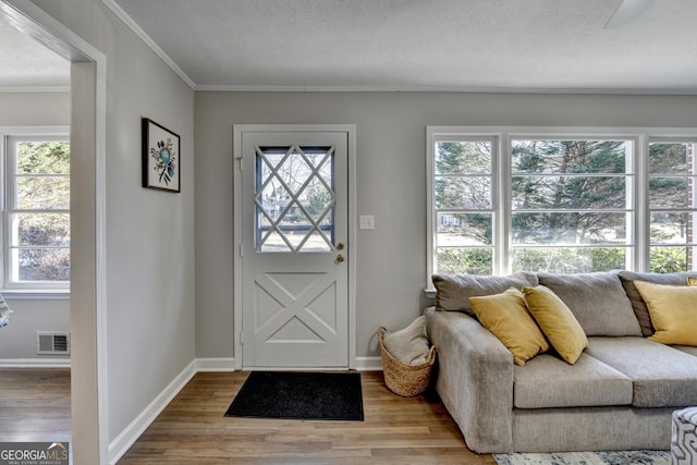 entryway featuring ornamental molding, a wealth of natural light, and hardwood / wood-style flooring