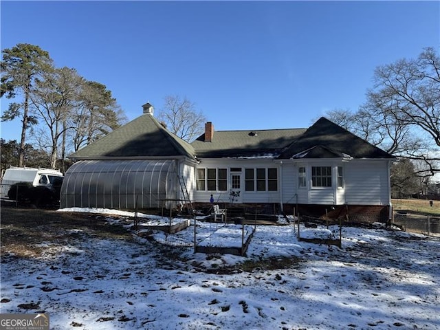 snow covered house featuring a sunroom