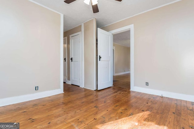 empty room with ceiling fan, wood-type flooring, and a textured ceiling