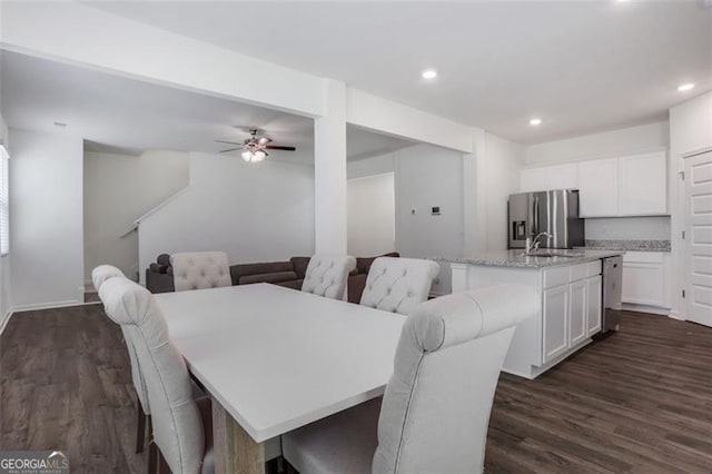 dining space featuring ceiling fan, sink, and dark wood-type flooring