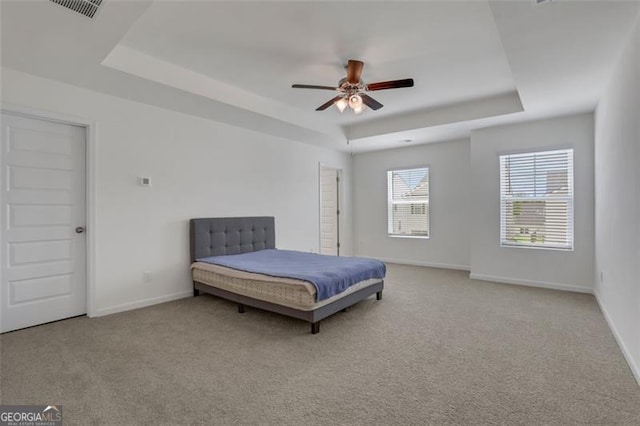 carpeted bedroom with a tray ceiling and ceiling fan