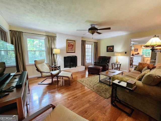 living room with a brick fireplace, light hardwood / wood-style flooring, plenty of natural light, and ceiling fan