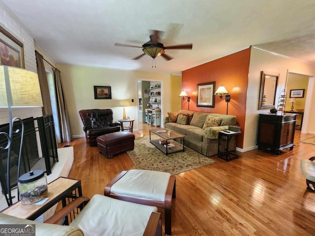 living room featuring a brick fireplace, ceiling fan, built in shelves, and light hardwood / wood-style flooring