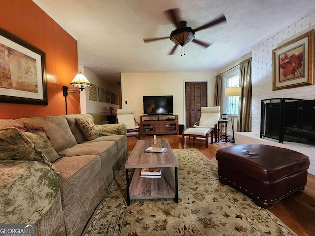 living room with ceiling fan, brick wall, a textured ceiling, wooden walls, and hardwood / wood-style flooring