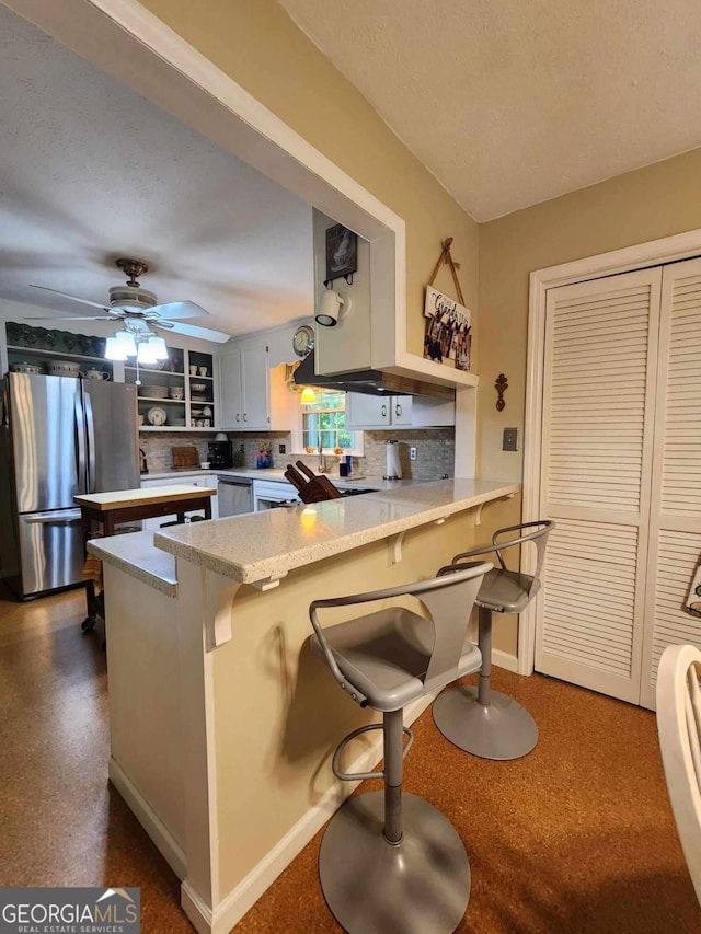 kitchen with a kitchen breakfast bar, white cabinetry, kitchen peninsula, and appliances with stainless steel finishes