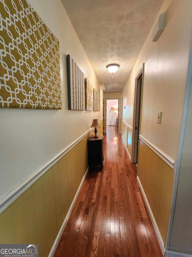 hallway with a textured ceiling and dark wood-type flooring