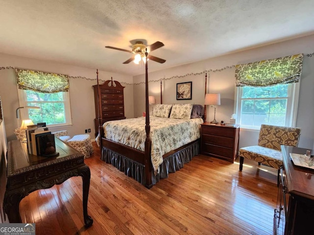 bedroom featuring ceiling fan, a textured ceiling, and light wood-type flooring