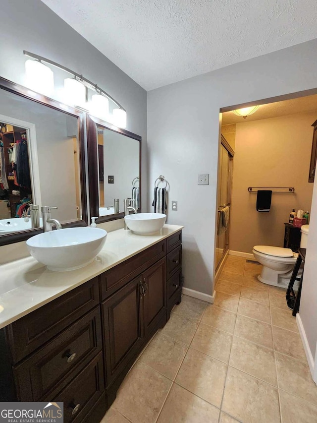 bathroom featuring tile patterned flooring, vanity, a shower with door, and a textured ceiling