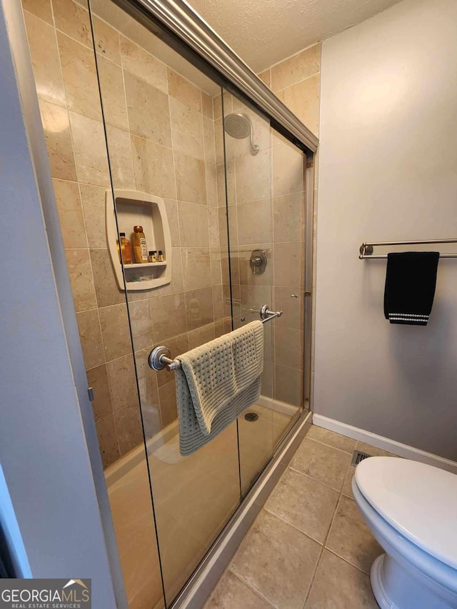 bathroom featuring tile patterned floors, toilet, and walk in shower