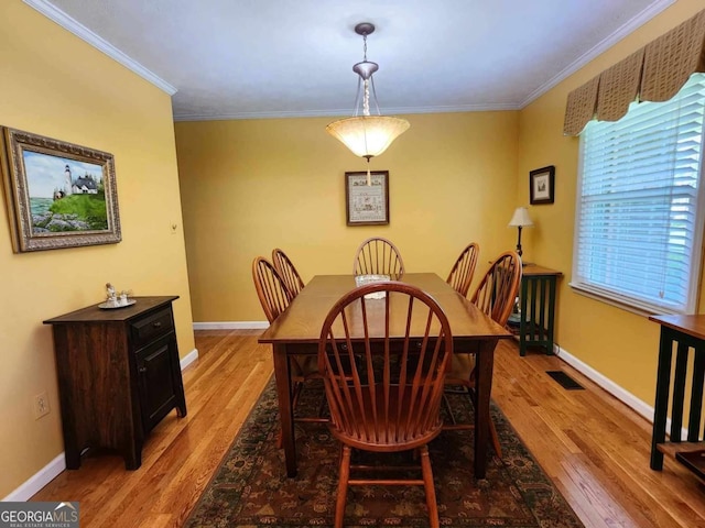 dining room featuring crown molding and light hardwood / wood-style flooring