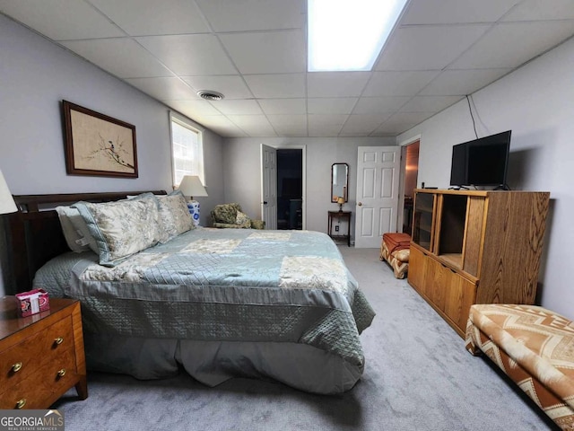 bedroom with a paneled ceiling and light colored carpet