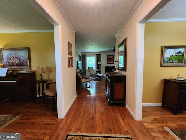 hall with hardwood / wood-style floors, a textured ceiling, and crown molding