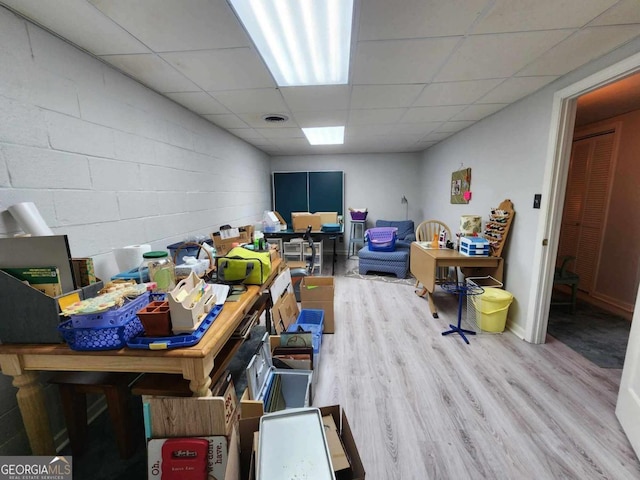 basement with a drop ceiling and wood-type flooring