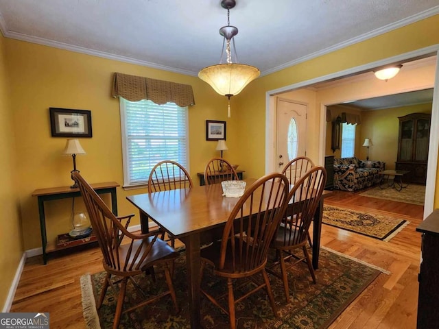 dining space with light hardwood / wood-style floors and crown molding