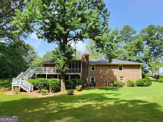 back of house featuring a sunroom, a wooden deck, cooling unit, and a lawn