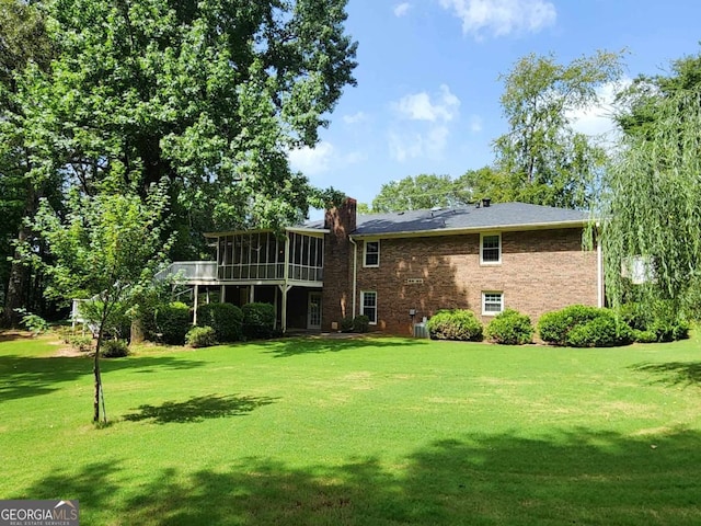 back of house featuring a yard and a sunroom