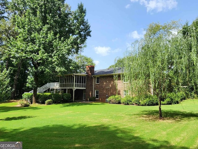 rear view of property featuring a sunroom and a lawn