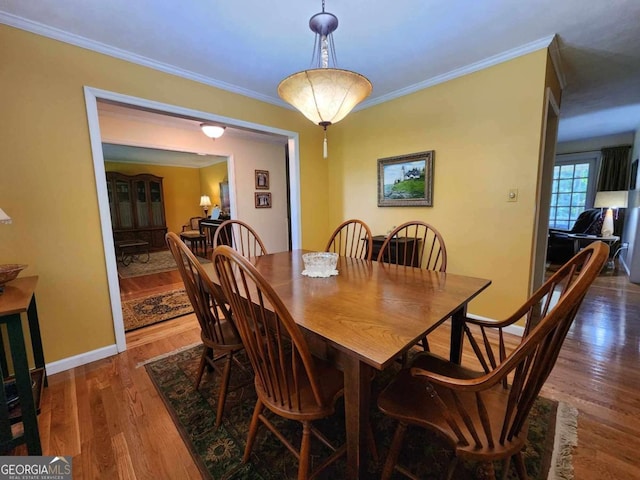 dining space with dark wood-type flooring and ornamental molding