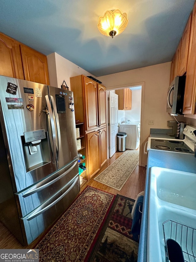 kitchen featuring washer and clothes dryer, wood-type flooring, and stainless steel appliances