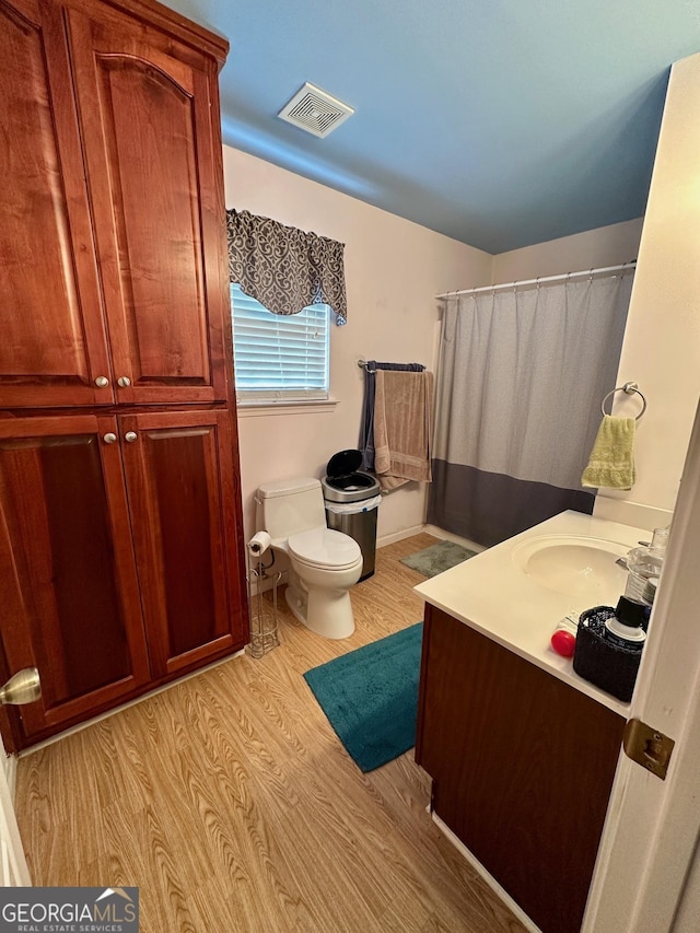 bathroom with wood-type flooring, toilet, and vanity