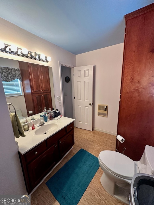 bathroom featuring hardwood / wood-style flooring, vanity, toilet, and heating unit