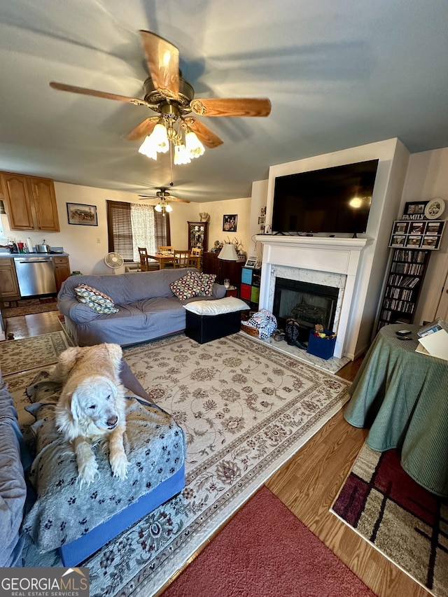 living room with ceiling fan, wood-type flooring, and a premium fireplace