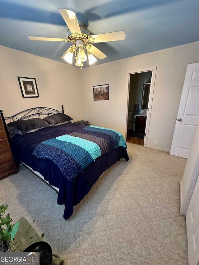 bedroom with connected bathroom, light colored carpet, and ceiling fan