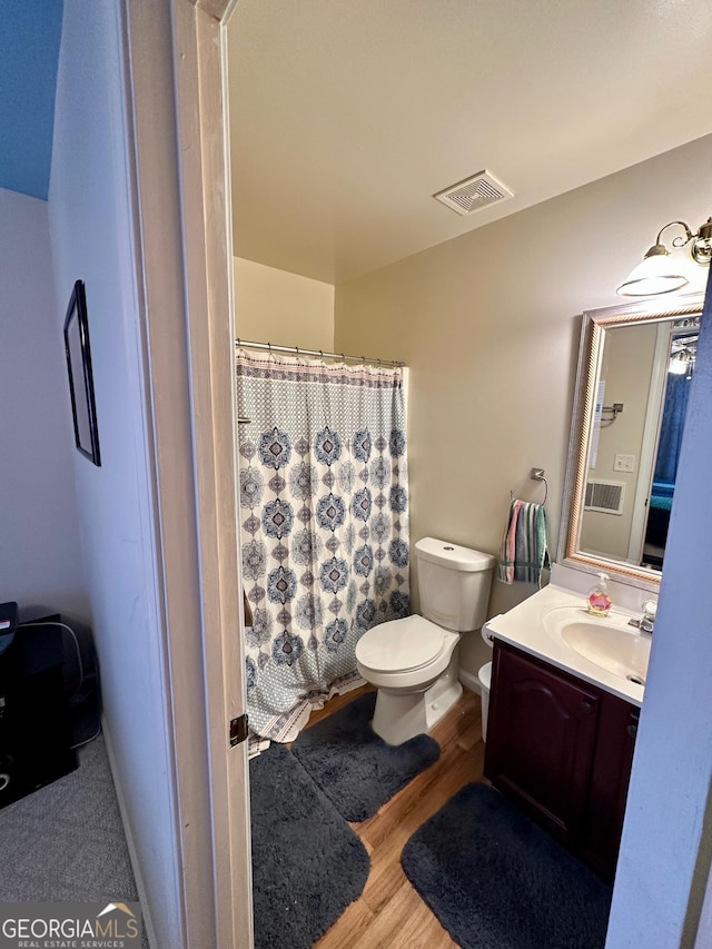 bathroom with wood-type flooring, toilet, and vanity