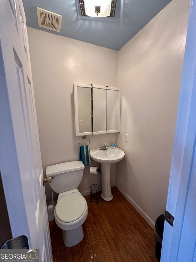 bathroom featuring wood-type flooring, sink, and toilet