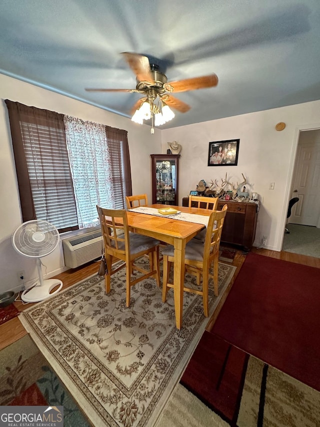 dining area featuring a wall mounted air conditioner, hardwood / wood-style flooring, and ceiling fan