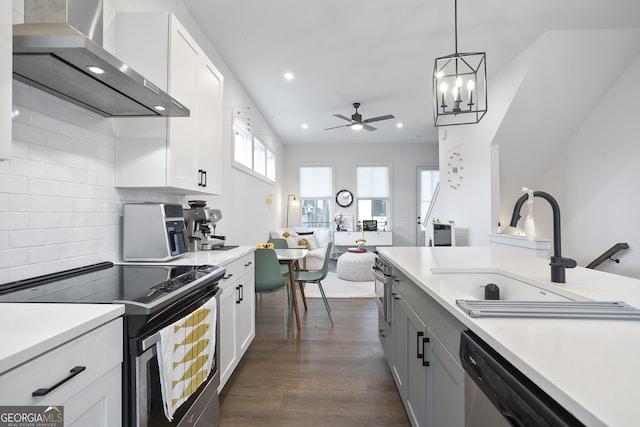 kitchen with white cabinetry, wall chimney range hood, backsplash, ceiling fan with notable chandelier, and appliances with stainless steel finishes