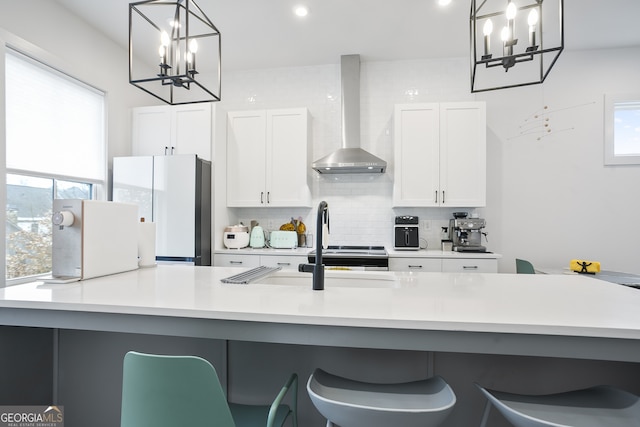 kitchen featuring white cabinets, hanging light fixtures, wall chimney exhaust hood, and white fridge