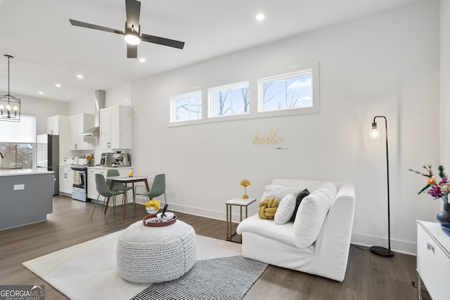 living room with ceiling fan with notable chandelier, dark wood-type flooring, and sink