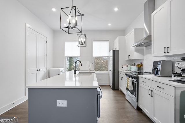 kitchen with appliances with stainless steel finishes, sink, a kitchen island with sink, and wall chimney range hood