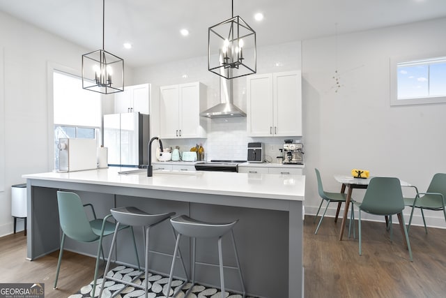 kitchen with appliances with stainless steel finishes, pendant lighting, white cabinetry, and wall chimney exhaust hood