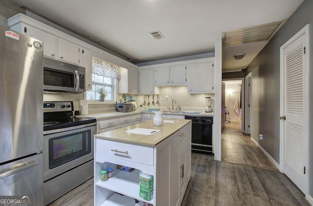 kitchen with appliances with stainless steel finishes, dark wood finished floors, and white cabinetry