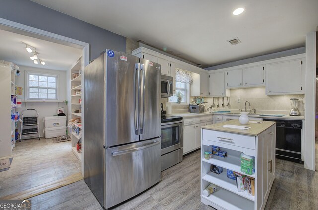 kitchen featuring stainless steel appliances, visible vents, light wood-style floors, white cabinets, and a center island