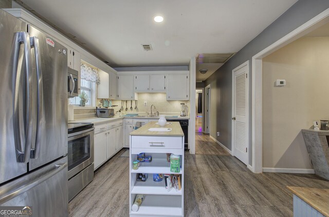 kitchen featuring white cabinetry, appliances with stainless steel finishes, a wealth of natural light, and a kitchen island