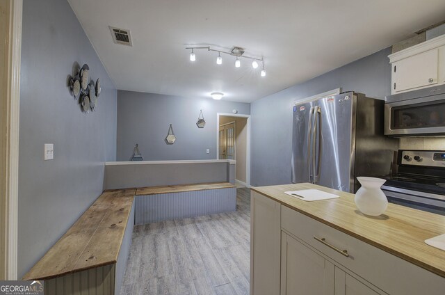 kitchen featuring white cabinets, appliances with stainless steel finishes, a kitchen island, sink, and light hardwood / wood-style flooring