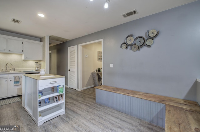 kitchen with light wood-style flooring, a sink, visible vents, white cabinetry, and light countertops