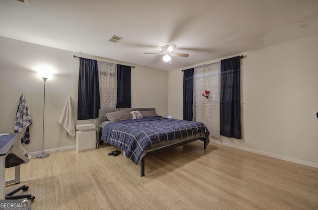 bedroom featuring ceiling fan, wood finished floors, visible vents, and baseboards