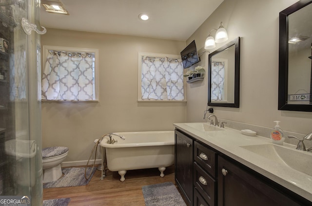 bathroom featuring toilet, a freestanding bath, a sink, and wood finished floors