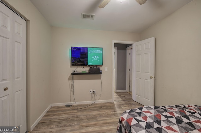 bedroom with a ceiling fan, visible vents, baseboards, and wood finished floors