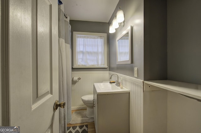 full bathroom featuring a wainscoted wall, vanity, and toilet