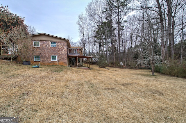 exterior space with a lawn, stairs, a wooden deck, central AC, and brick siding