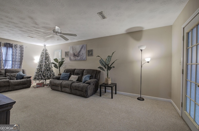 carpeted living room with baseboards, ceiling fan, visible vents, and a textured ceiling