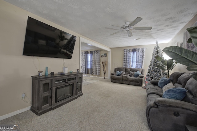 living room featuring ceiling fan, light colored carpet, and a textured ceiling