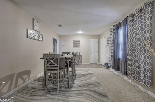 carpeted dining area featuring visible vents and baseboards