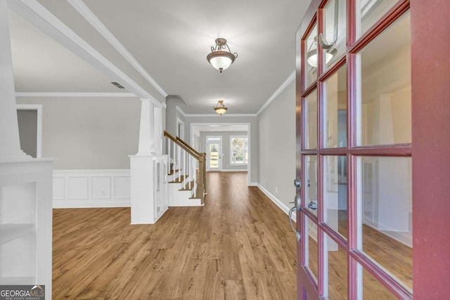 entrance foyer with light hardwood / wood-style flooring, crown molding, and ornate columns